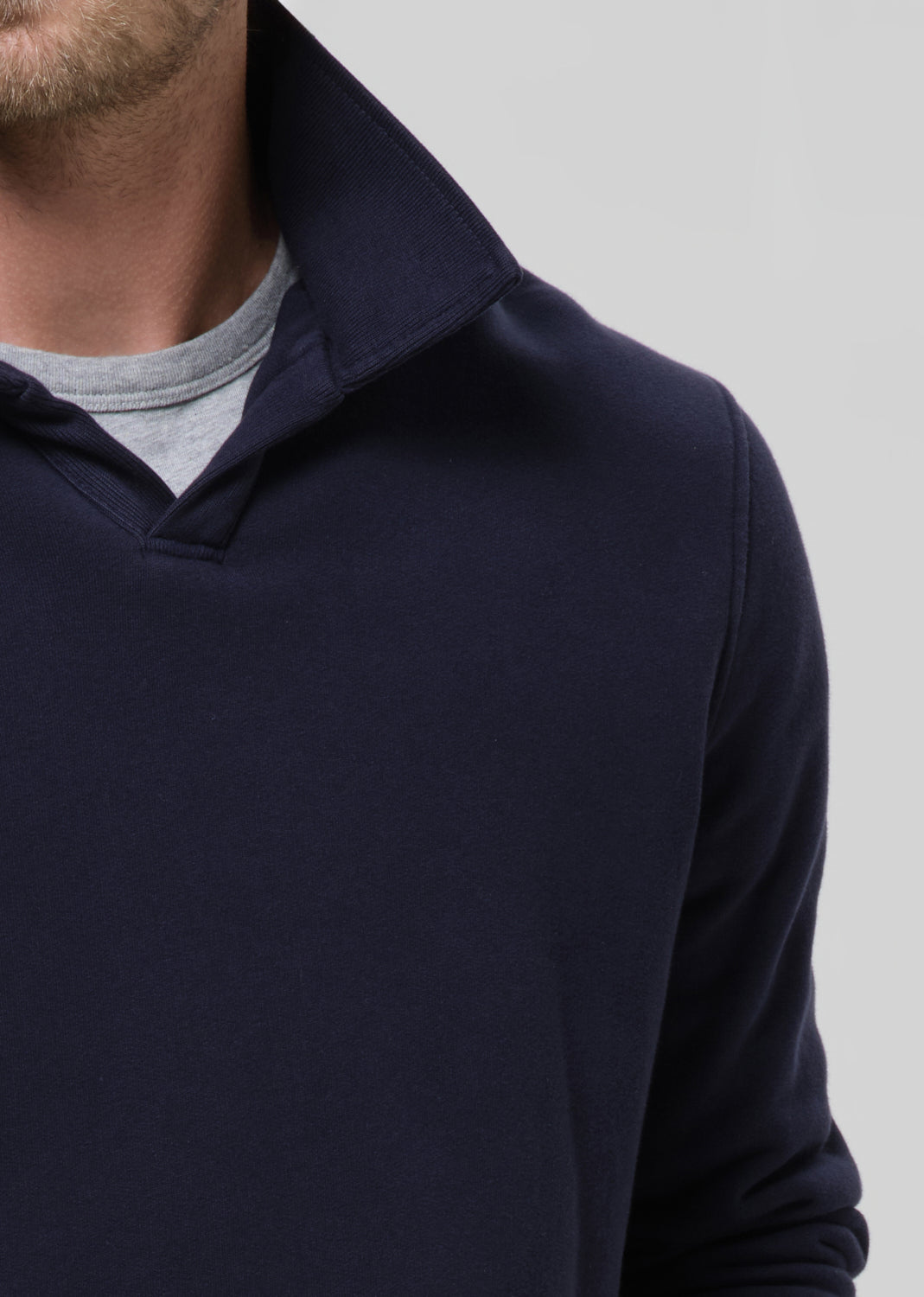 Navy blue sweater worn by a person on a grey background