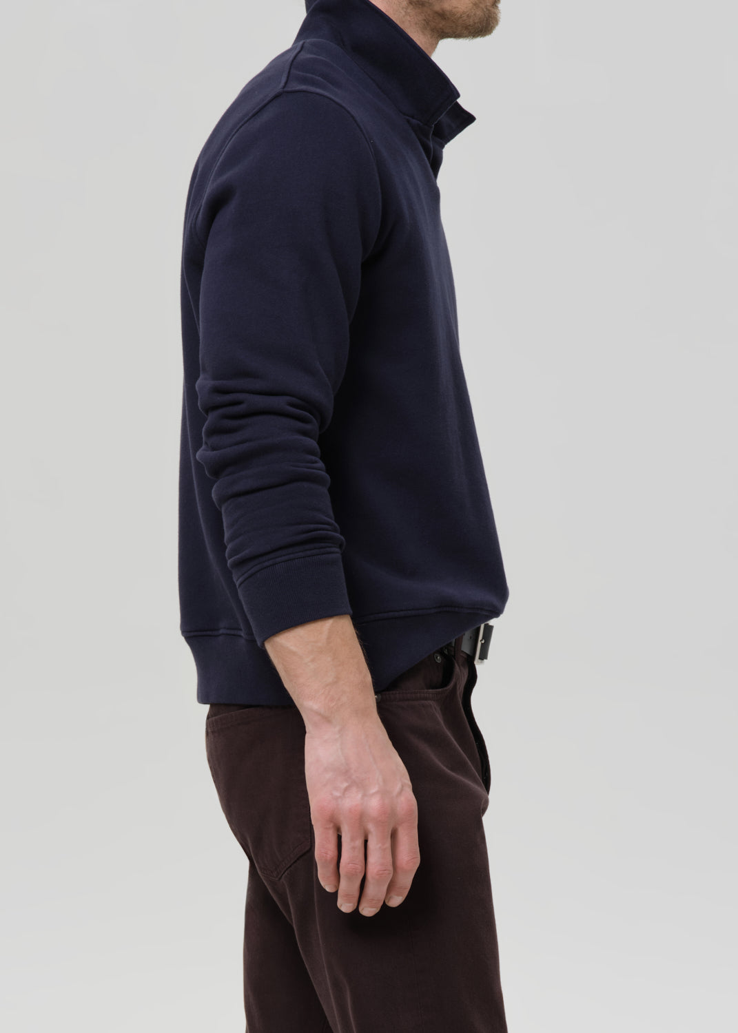Person wearing a navy blue pullover with a zipper on a grey background