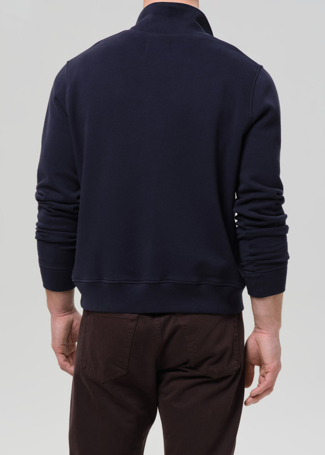Person wearing a navy blue jacket on a grey background