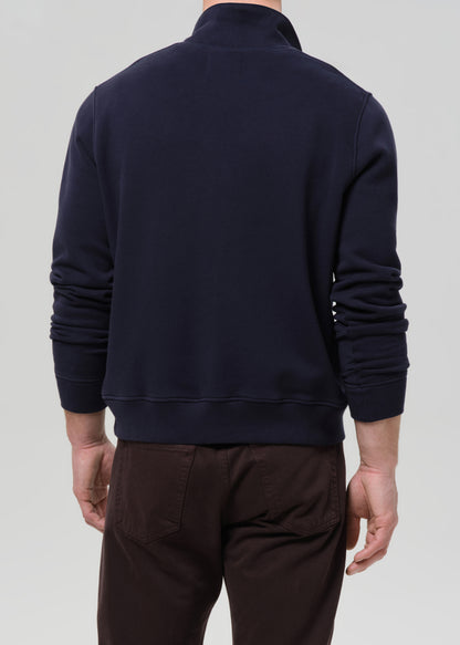 Person wearing a navy blue jacket on a grey background