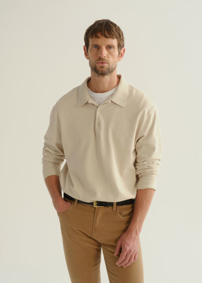 Person wearing a cream long sleeve polo pullover and tan pants, front cropped view on a light grey background.