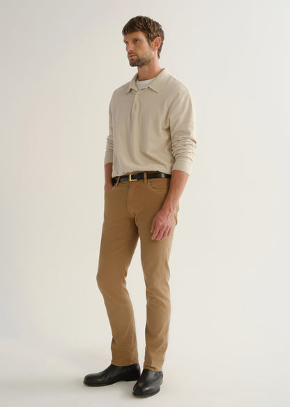 Person wearing a cream long sleeve polo pullover, tan pants, and black boots, angled front full body view on a light grey background.