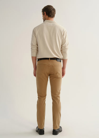 Person wearing a cream long sleeve polo pullover, tan pants, and black boots, back full body view on a light grey background.