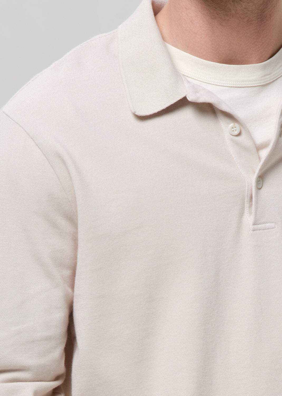 Close-up of a beige polo sweater on a grey background