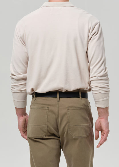 Person wearing a beige polo sweater and khaki pants on a grey background