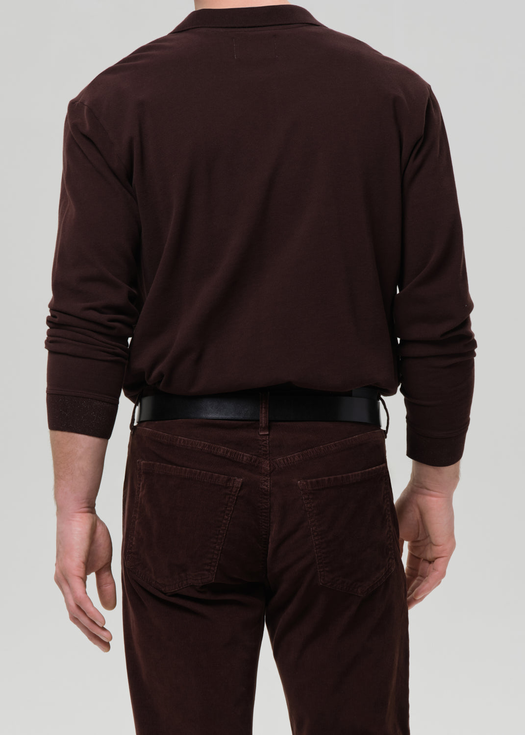 Man wearing a brown polo shirt and pants on a grey background