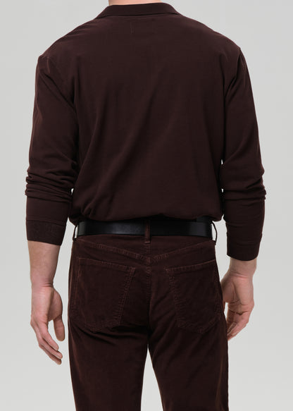 Man wearing a brown polo shirt and pants on a grey background