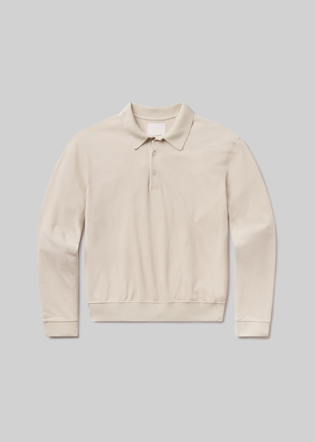 Flat lay shot of a beige polo sweater on a grey background