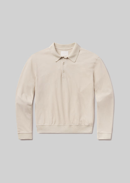 Flat lay shot of a beige polo sweater on a grey background