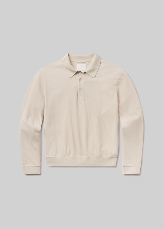 Flat lay shot of a beige polo sweater on a grey background