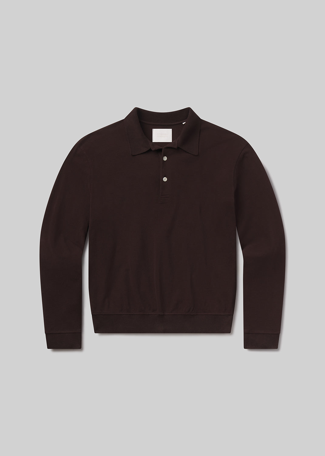 Flat lay of brown long-sleeve polo shirt on a grey background