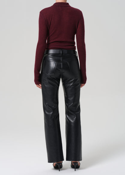 Person wearing a burgundy sweater and black leather pants on a white background